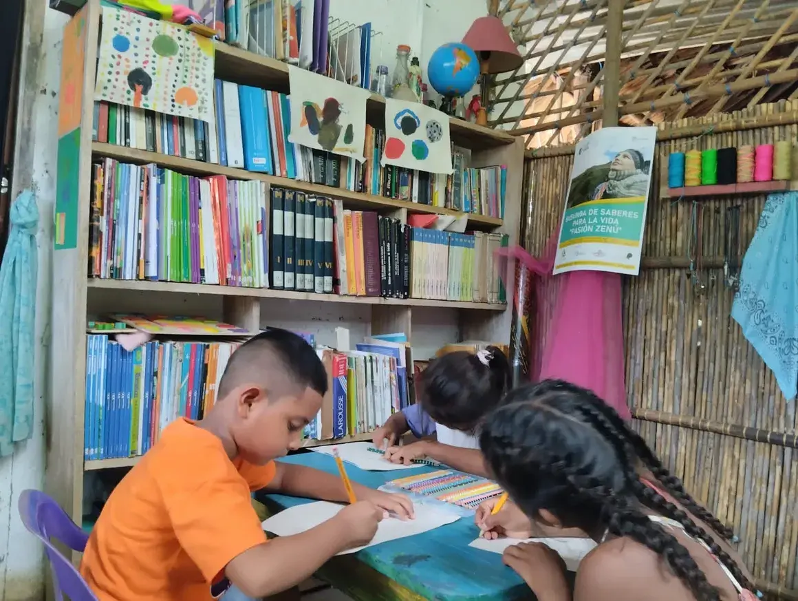 Niños y niñas dibujando en una biblioteca comunitaria